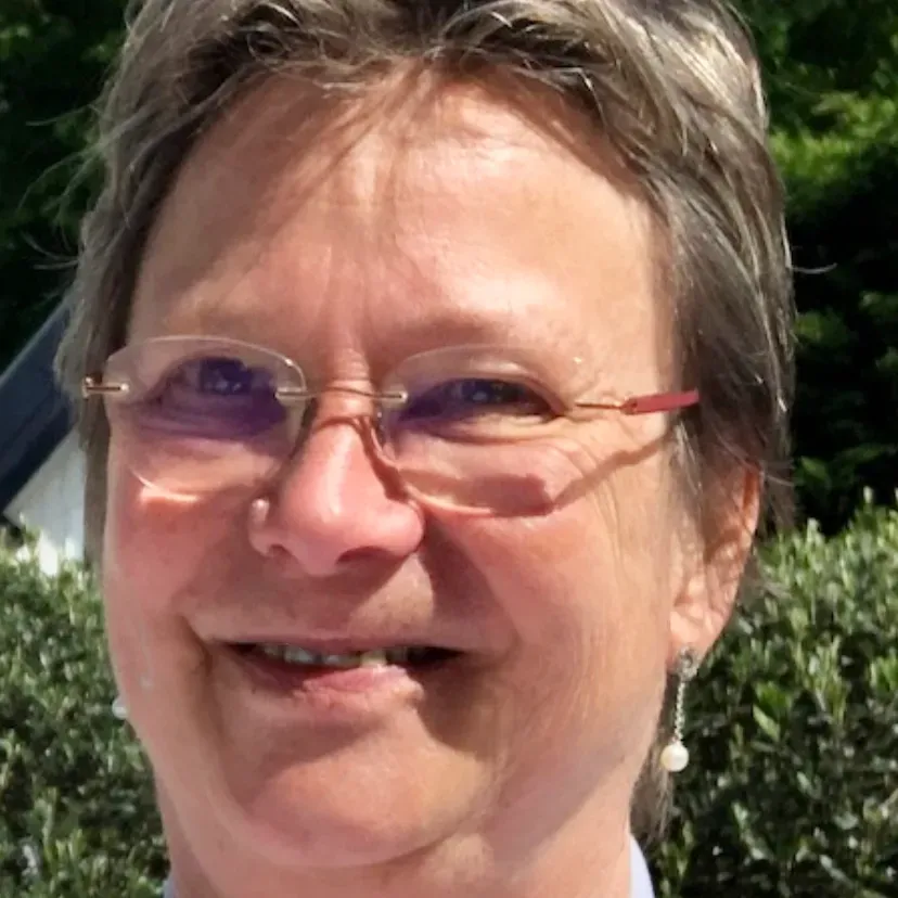 Marianne Kant-Schaps Profilbild. Sie steht vor einer grünen Hecke und trägt Brille.