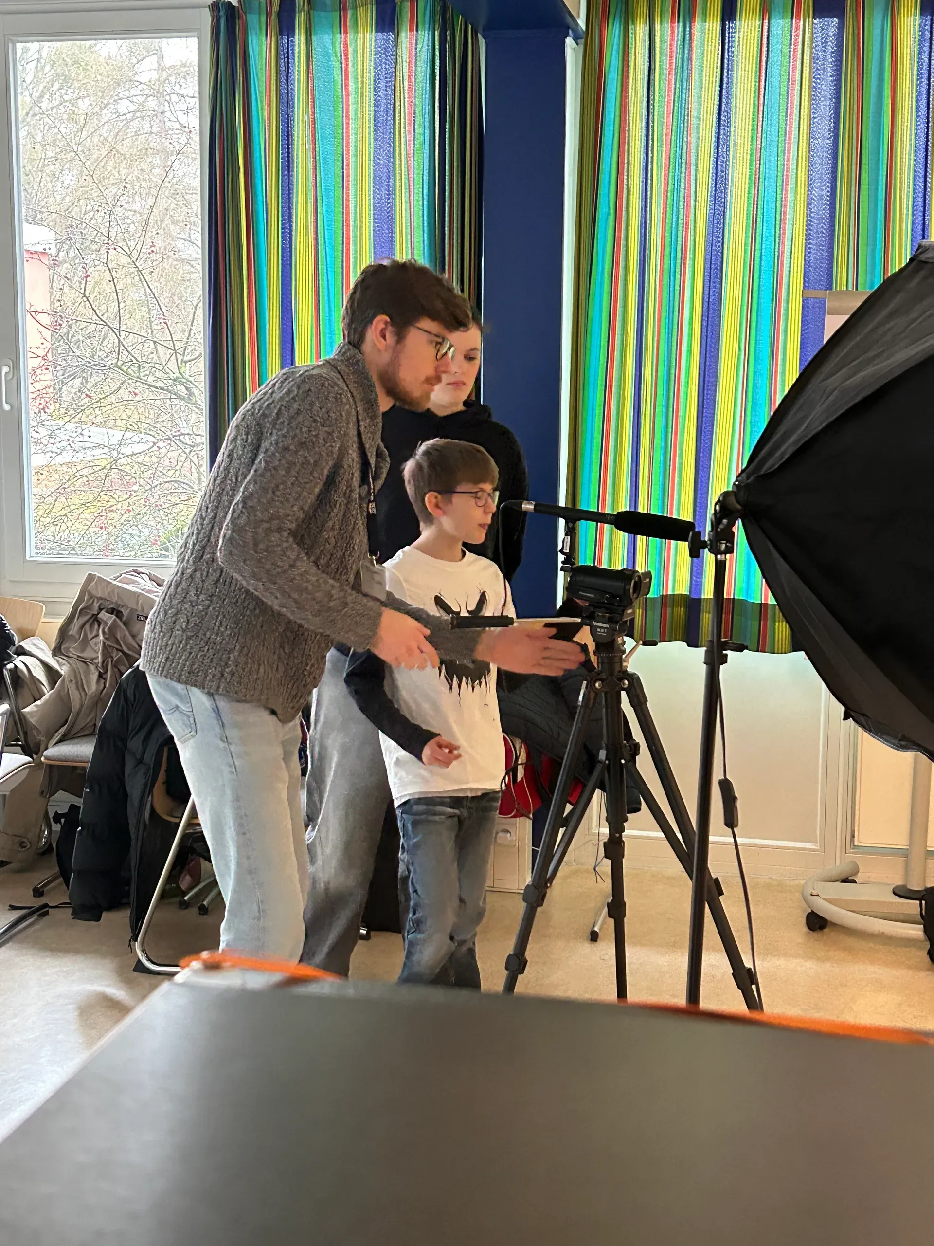 Eine Übungsleitung erklärt einem Schüler eine Kamera.